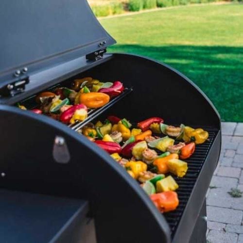 Camp Chef SmokePro XT24 – pohled zepředu s otevřeným víkem, viditelné nerezové grilovací rošty a ohřívací stojan