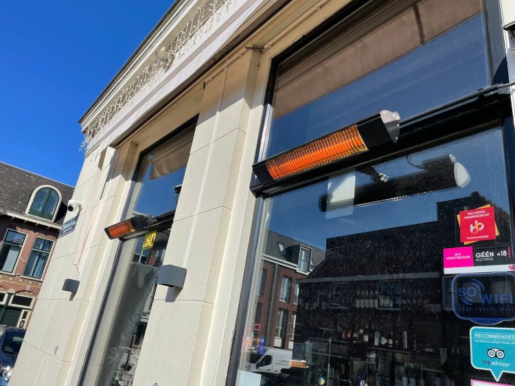 Infrazářič Tansun Bahama Elite 2,0 kW v atmosférické instalaci na luxusní restaurační terase – ukázka diskrétního karbonového zářiče s minimálním světelným výstupem nad stoly s tlumeným osvětlením a svíčkami