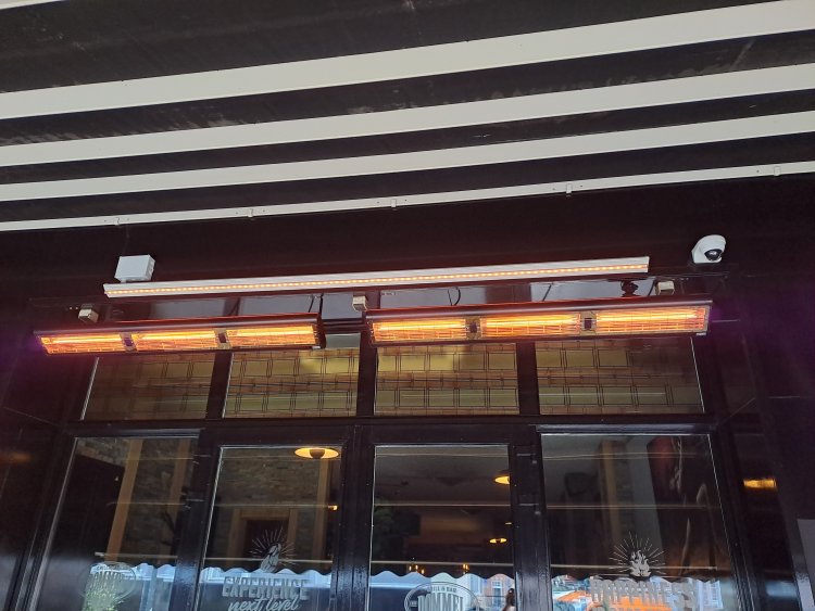 Infrazářič Tansun Monaco XL IPT Carbon 6,0 kW v atmosférické instalaci na rozlehlé hotelové terase – ukázka diskrétního karbonového zářiče s minimálním světelným výstupem a třemi topnými elementy zajišťujícími rovnoměrné teplo na velké ploše